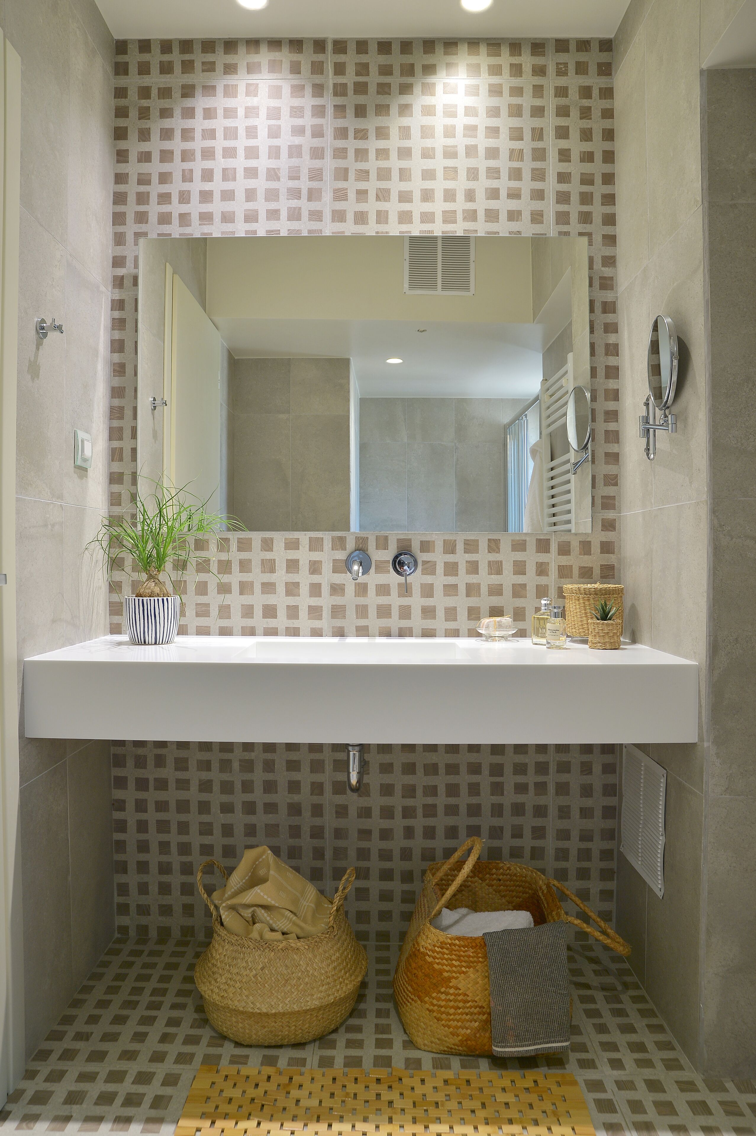 A bathroom with a white sink, a mirror, a potted plant, and a woven basket.
