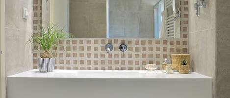 A bathroom with a white sink, a mirror, a potted plant, and a woven basket.