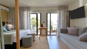 Een moderne hotelkamer met een bed, een bank, een tafeltje en een balkon met uitzicht.