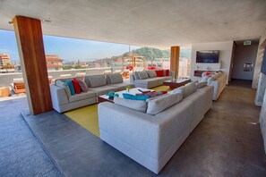 A spacious living area with a large grey sectional sofa, a coffee table, and a TV mounted on the wall.