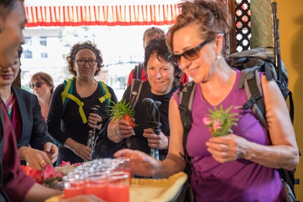 Un grupo de personas sentadas a una mesa con bebidas y flores, algunos con mochilas.