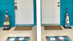 A wooden sign above two white doors with teal walls, a welcome sign, and a beach-themed mat. - Perfect Summer backyard, Steps to Beach, Bikes, boogie-board, bunk beds, Grill (St Augustine)
