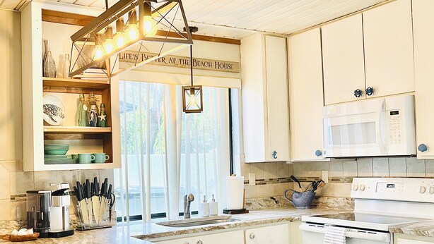 A modern kitchen with a marble island, white cabinetry, a built-in oven, and a microwave. - Perfect Summer backyard, Steps to Beach, Bikes, boogie-board, bunk beds, Grill (St Augustine)