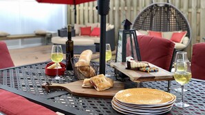 An outdoor dining area with a metal table, red chairs, a red umbrella, a lantern, and a bottle of wine. - Perfect Summer backyard, Steps to Beach, Bikes, boogie-board, bunk beds, Grill (St Augustine)