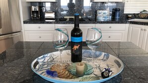A kitchen with white cabinets, a black countertop, and a decorative plate with a nautical theme.