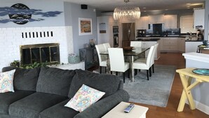 A modern living room with a gray sofa, a fireplace, and a dining area with a chandelier.