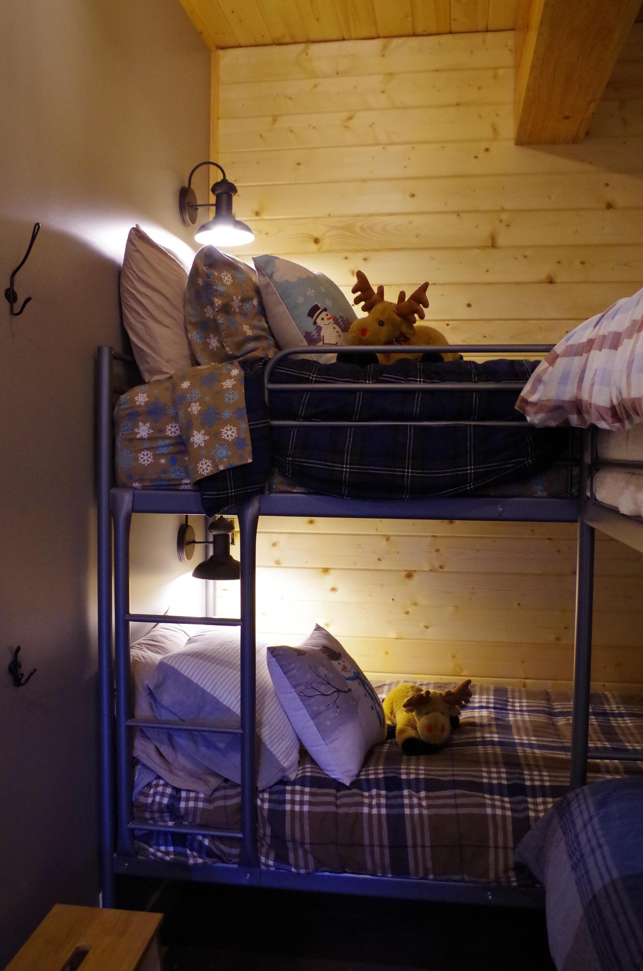 A bunk bed with a plush toy on the top bunk and a lamp on the side.