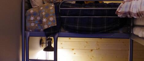 A bunk bed with a plush toy on the top bunk and a lamp on the side.