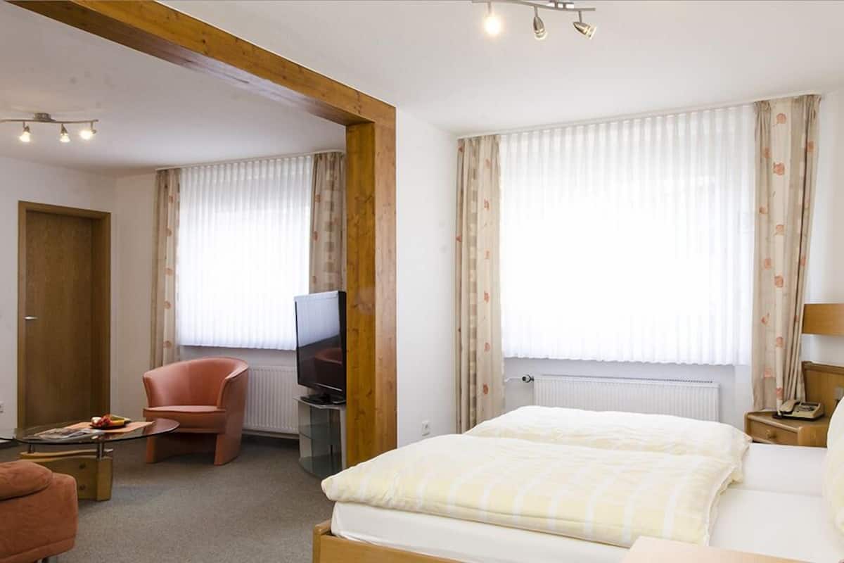 Une chambre d’hôtel avec un lit, une télévision, une chaise et un bureau.
