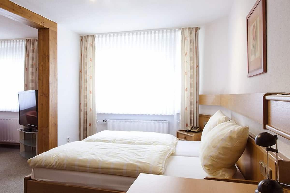 Une chambre d’hôtel avec un lit, une chaise, un bureau, une télévision et des rideaux.