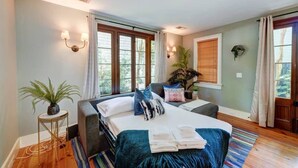 A bedroom with a bed, bedside tables, a window with curtains, and a potted plant. - Monaco Manor | Charleston Home w/ Rooftop Deck! (Charleston)
