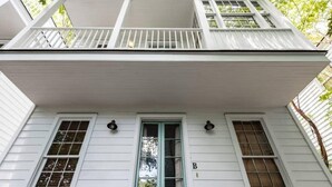 A two-story house with a front door, two windows on the first floor, and a balcony on the second floor. - Monaco Manor | Charleston Home w/ Rooftop Deck! (Charleston)
