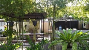 A covered outdoor seating area with a pergola, surrounded by lush greenery and potted plants. - Baan Rim Nam Resort (Phang Nga)