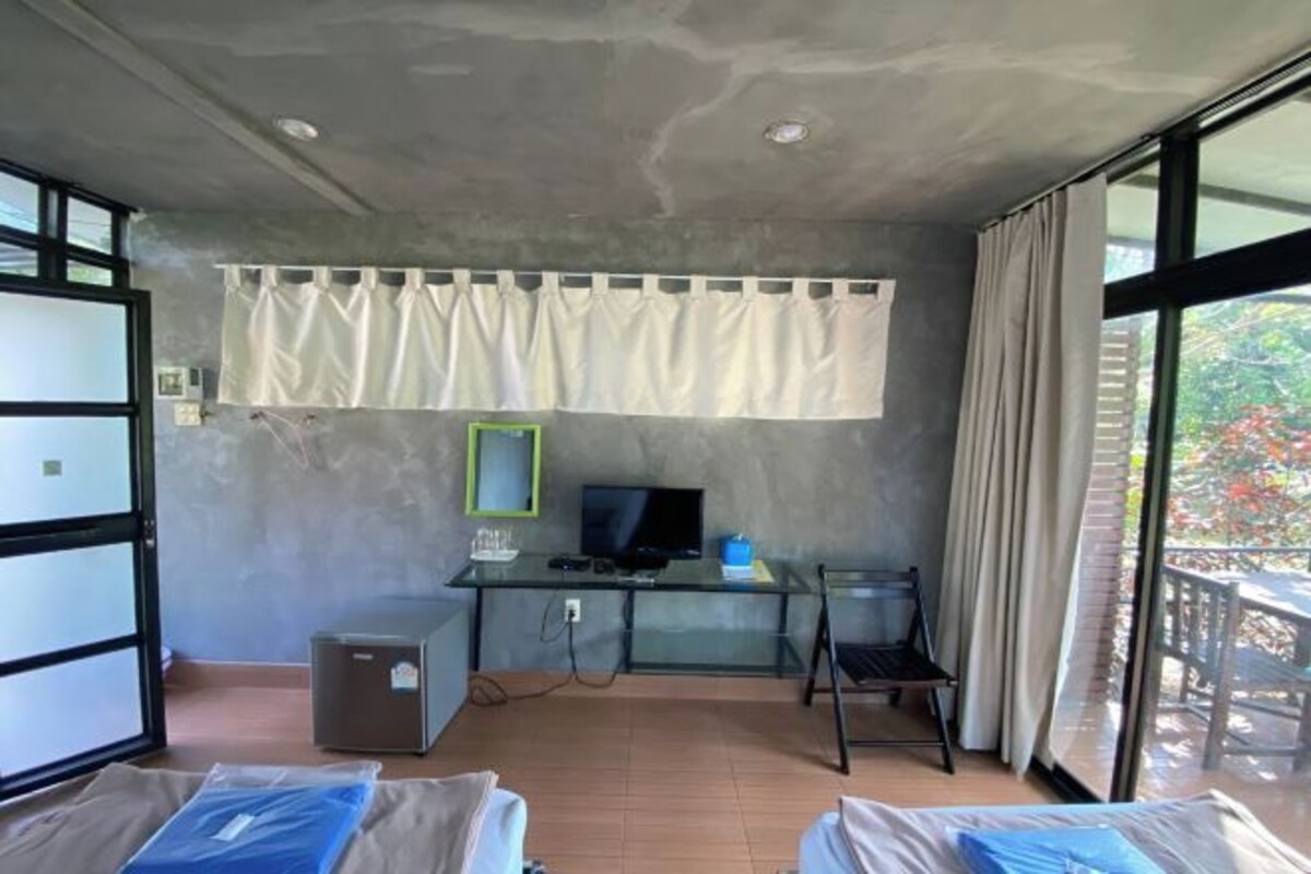A room with a glass desk, a television, a small cabinet, and a chair.