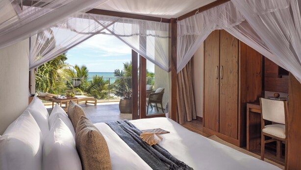 Un dormitorio con una cama grande, un armario de madera y vista al océano.