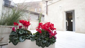 Een potplant met rode bloemen voor een gebouw met een klokkentoren.