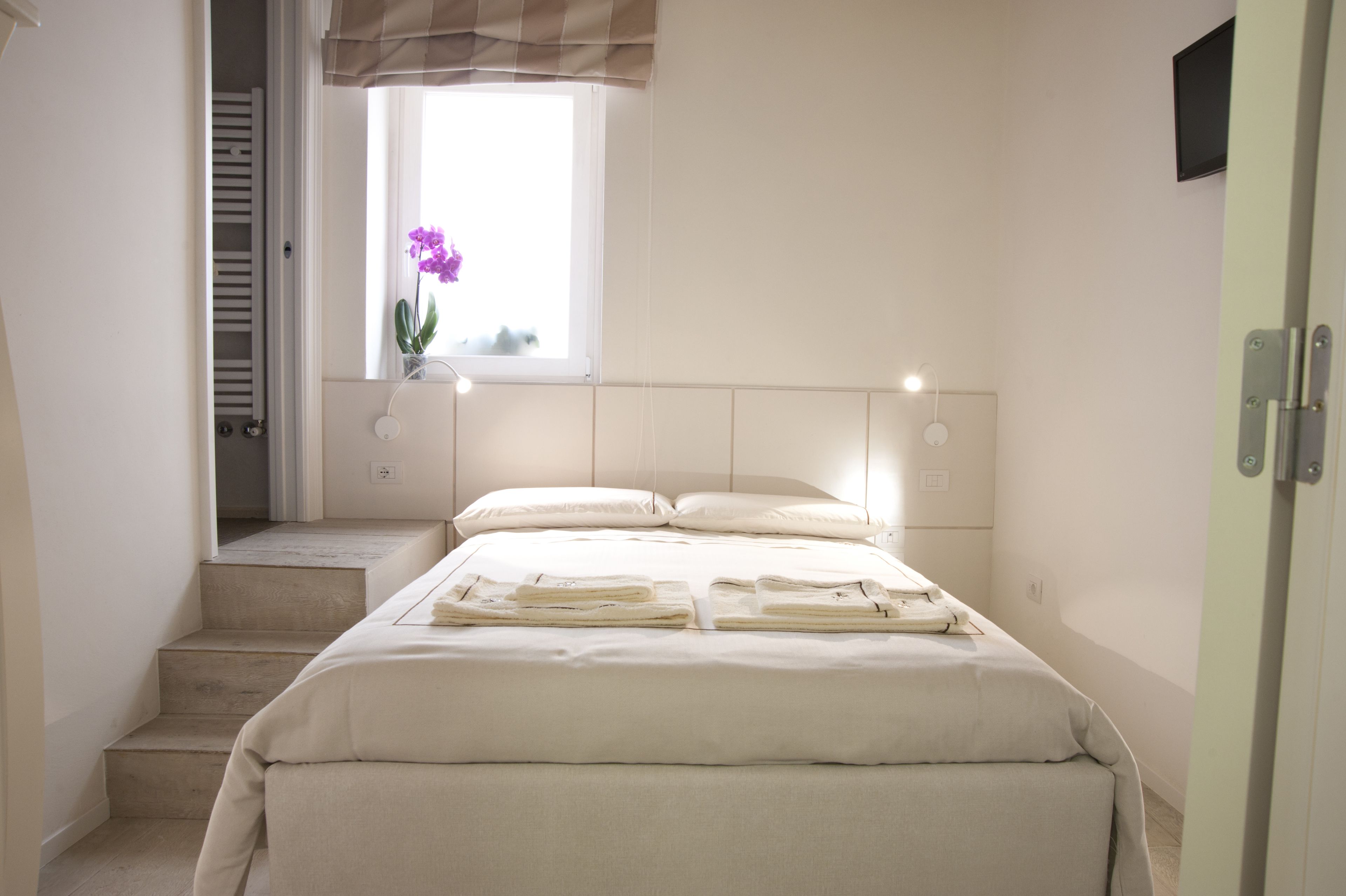 Un dormitorio con cama, ventana con vistas, mesita de noche y puerta.