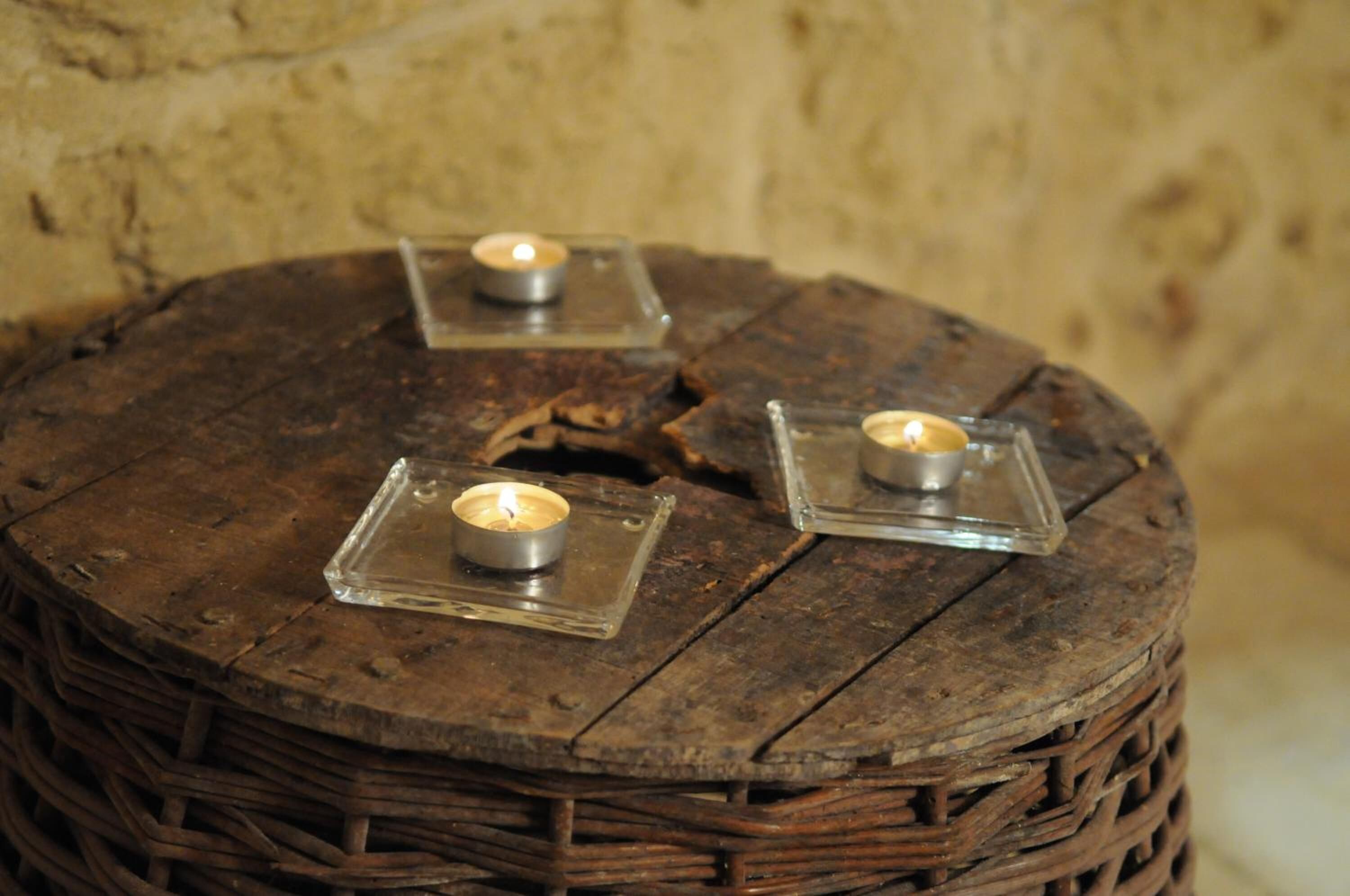 Three candles on a round wooden table with a textured surface.