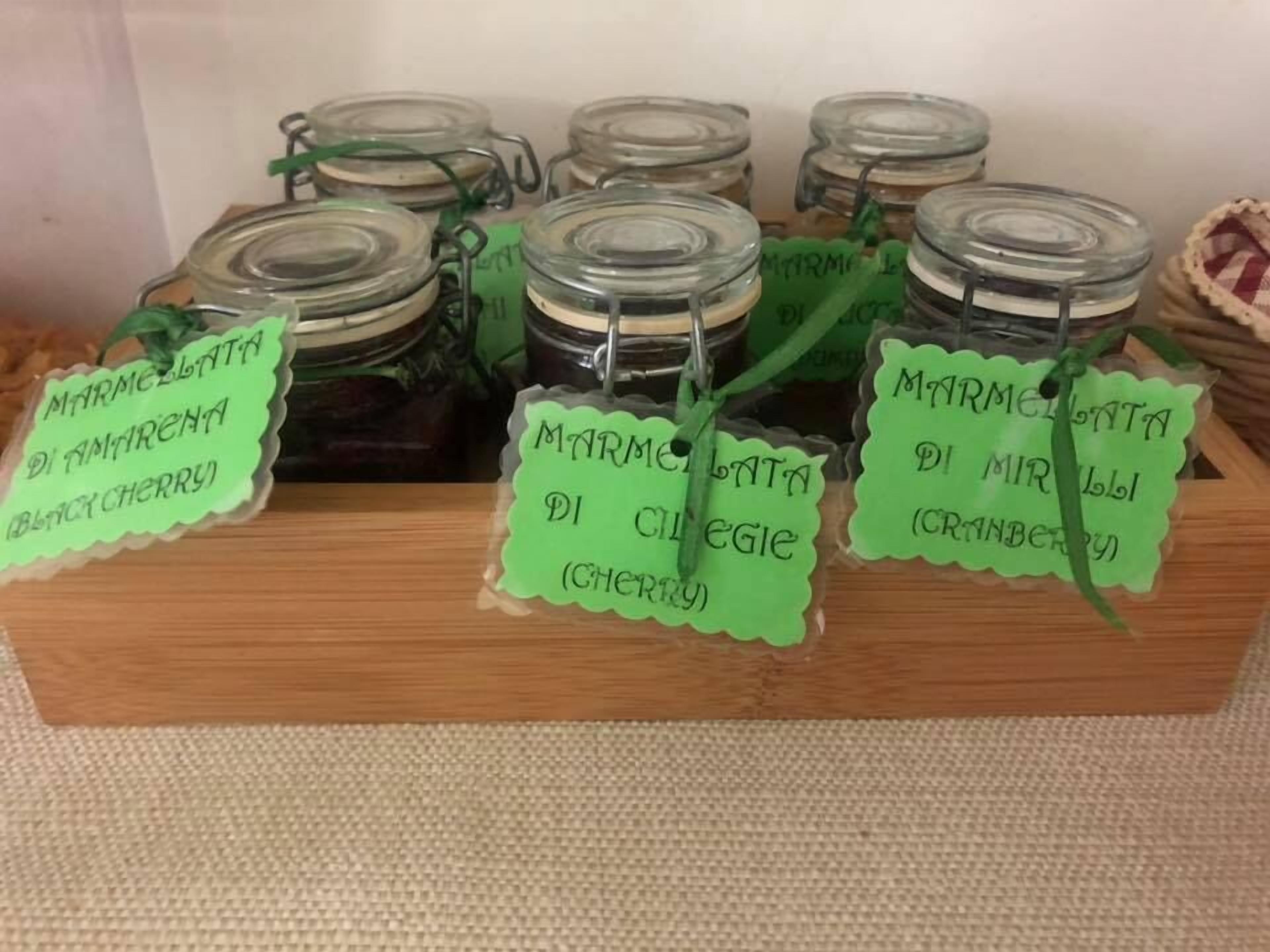 Des pots de confiture d’agrumes dont les étiquettes indiquent les saveurs, comme la cerise noire et la canneberge.