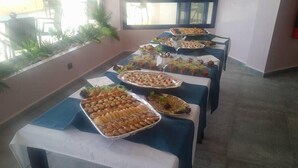 A buffet table with various food items, set up in a room with a tiled floor and a window in the background. - Le Temps Perdu (Oualidia)