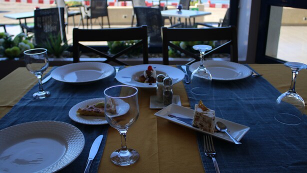 A table set for dining with plates, cutlery, and glasses, overlooking a beach. - Le Temps Perdu (Oualidia)