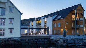 A waterfront hotel with a stone facade, multiple windows, and a wooden building with a balcony. - Stad Hotell (Stad)