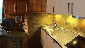A kitchen with wooden cabinets, a stainless steel sink, and a tiled backsplash.