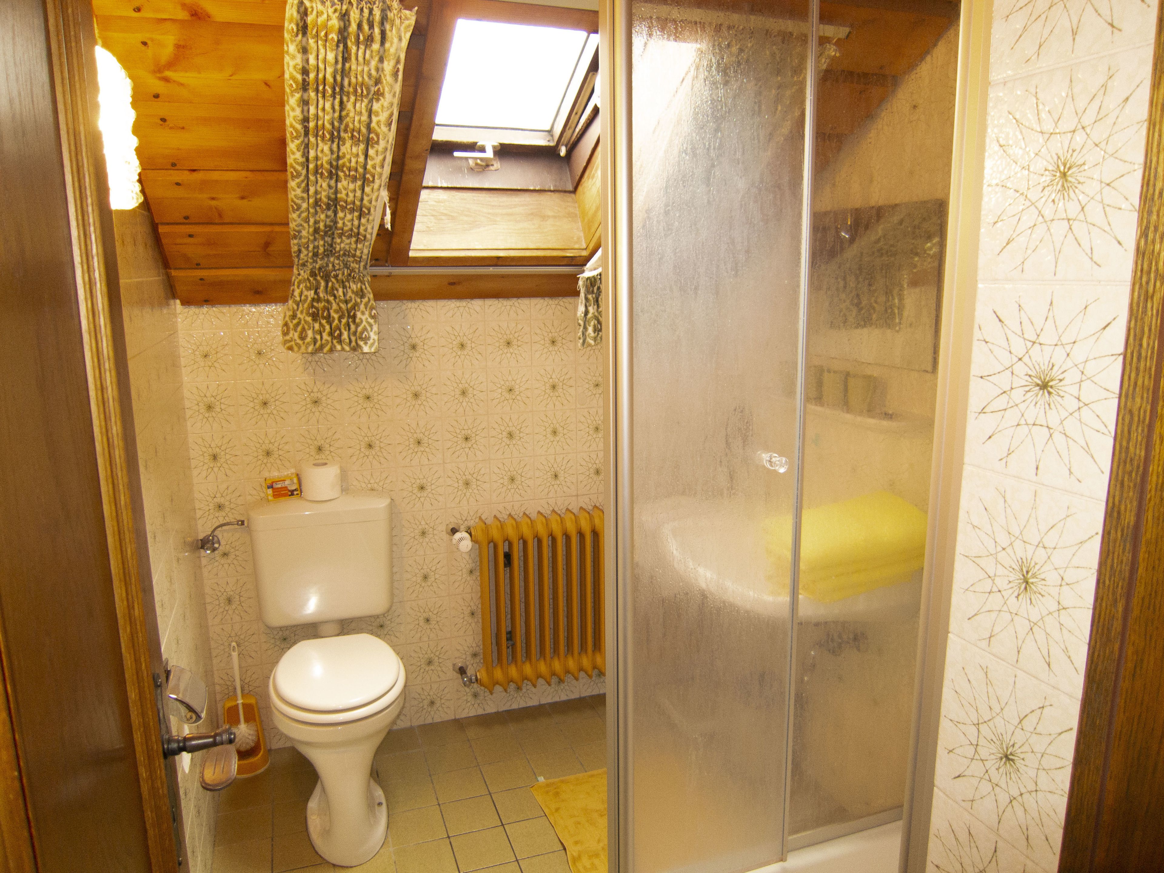 A bathroom with a toilet, a radiator, and a bathtub.