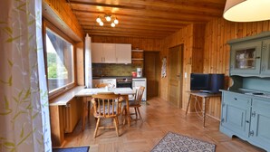 Un intérieur en bois comprenant une table à manger, des chaises, un coin cuisine et un téléviseur.