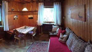 L’intérieur d’un chalet chaleureux, avec une table à manger en bois, des chaises, un canapé et un radiateur.