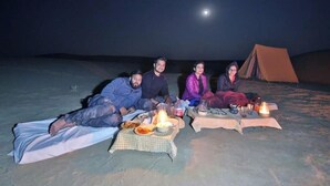 A group of people sitting on the ground with a tent in the background. - The Chirag Desert Camp Sam Sand Dunes (Jaisalmer)