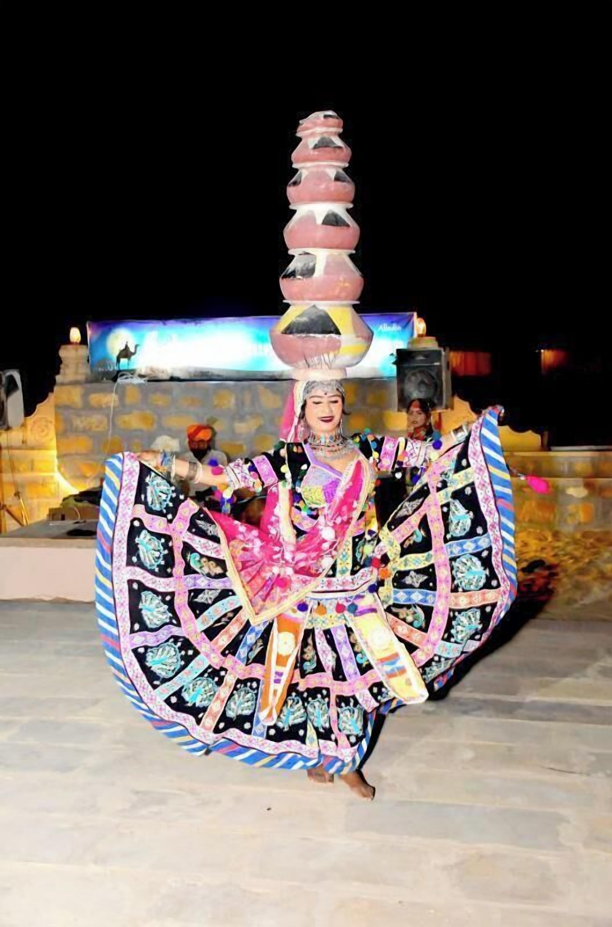 A person in traditional attire performing on a stage with a backdrop.