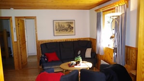 A cozy living room with a dark blue sofa, a round wooden coffee table, and a framed picture on the wall.