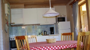 A compact kitchen with white cabinets, a microwave, a coffee maker, and a table set with a checkered tablecloth.