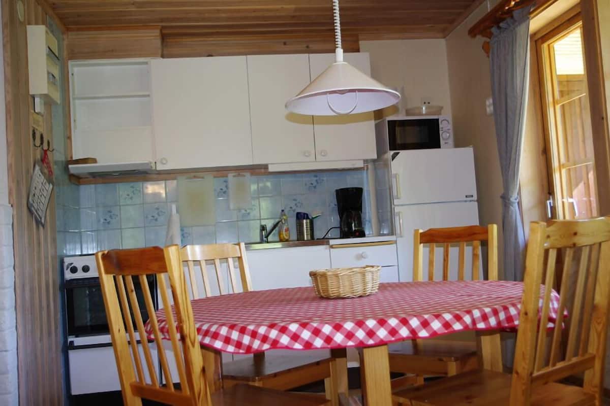 A compact kitchen with white cabinets, a microwave, a coffee maker, and a table set with a checkered tablecloth.