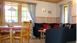 A cozy room with a wooden dining table, chairs, a sofa, and a small table with a basket.