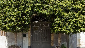 A dark wooden double door with a simple, arched top, set within a stone wall. - Alcalà Living B&B (Catania)