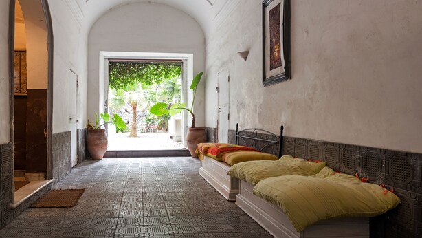 A hallway with a tiled floor, a bed with a headboard, a potted plant, and a framed picture on the wall. - Alcalà Living B&B (Catania)