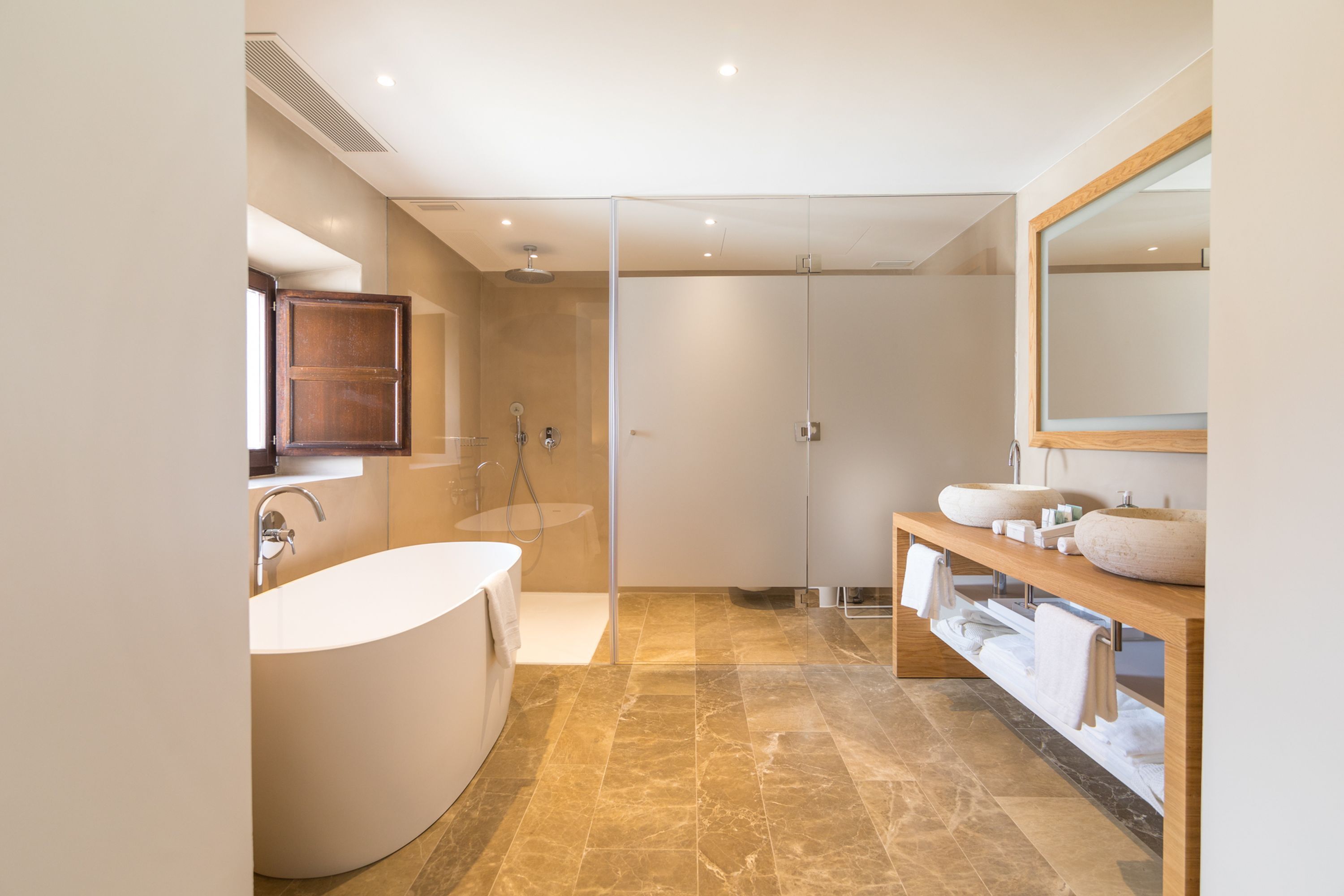 A modern bathroom with a freestanding bathtub, a large mirror, and a vanity with a bowl sink.