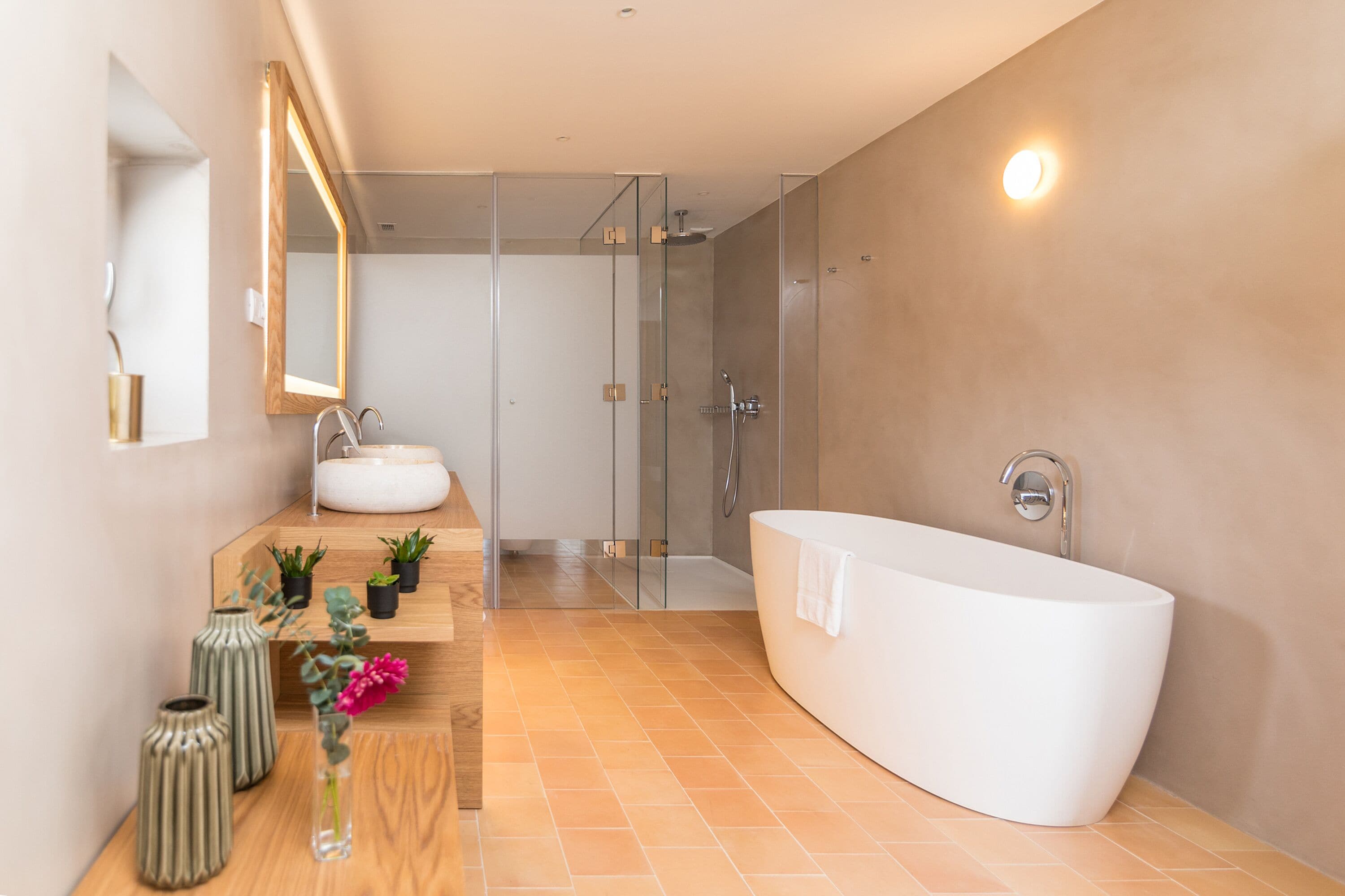 A modern bathroom with a freestanding bathtub, a glass-enclosed shower, and a vanity with a mirror and sink.