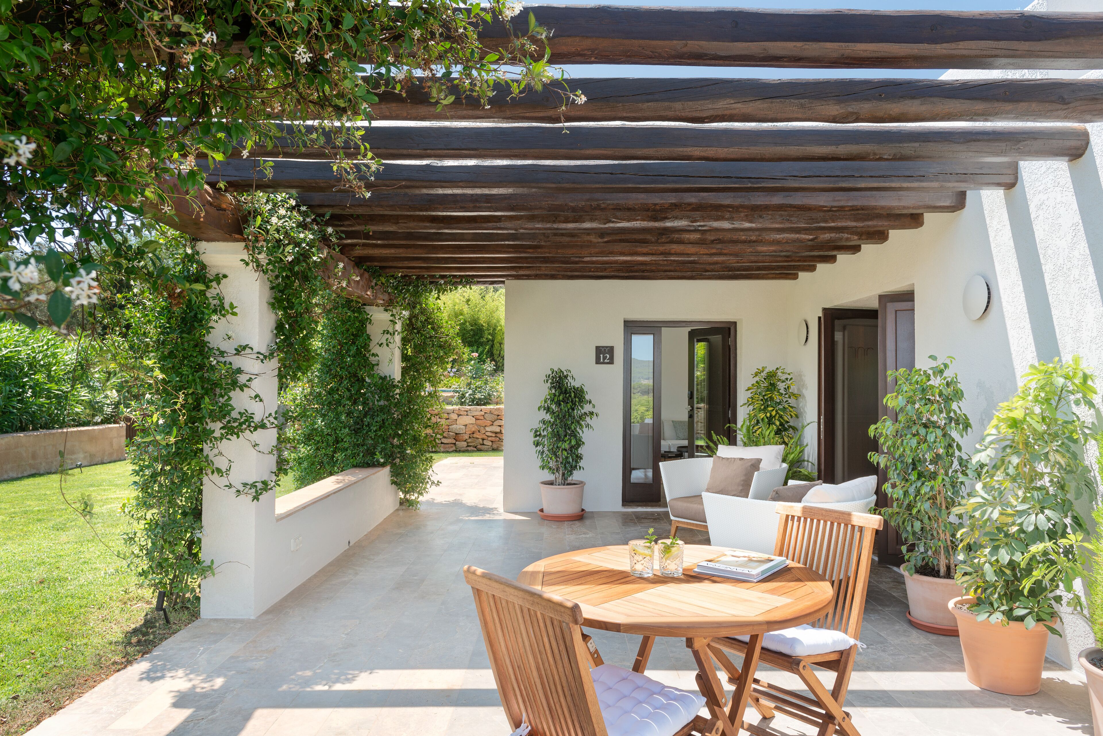 Une terrasse dotée de meubles en bois, de plantes en pot et d’une pergola.