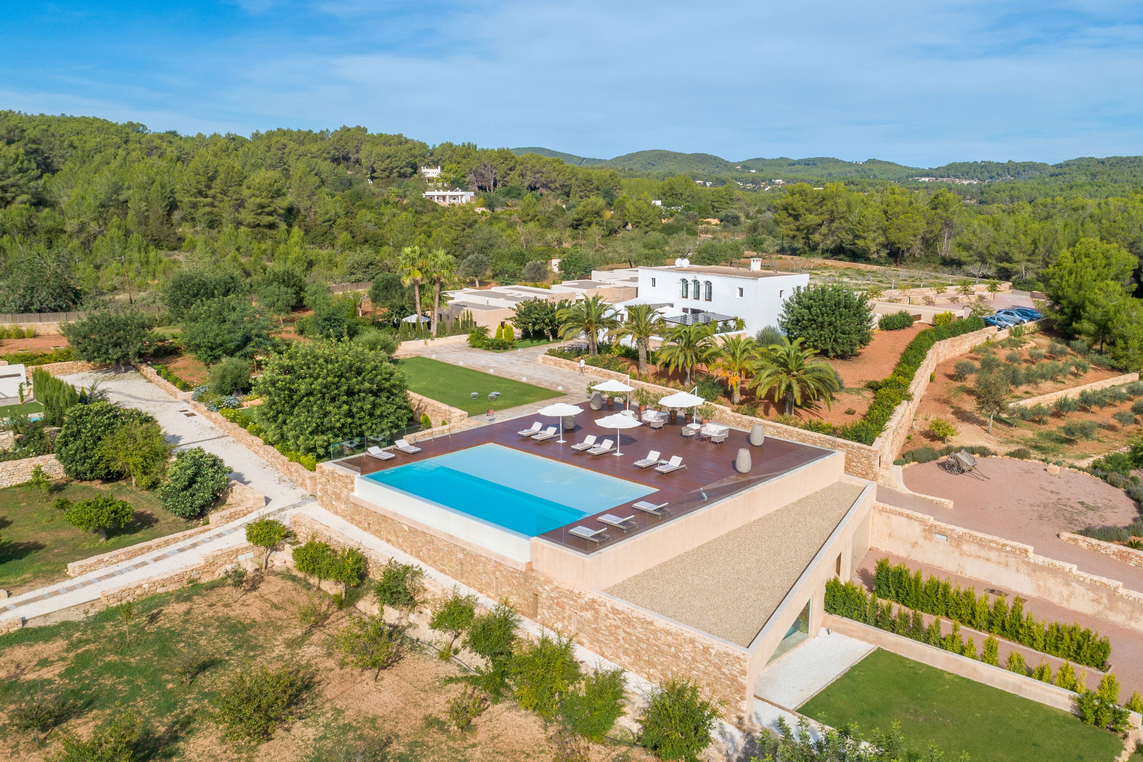 An aerial view of a property with a swimming pool, lounge chairs, and a landscaped garden.