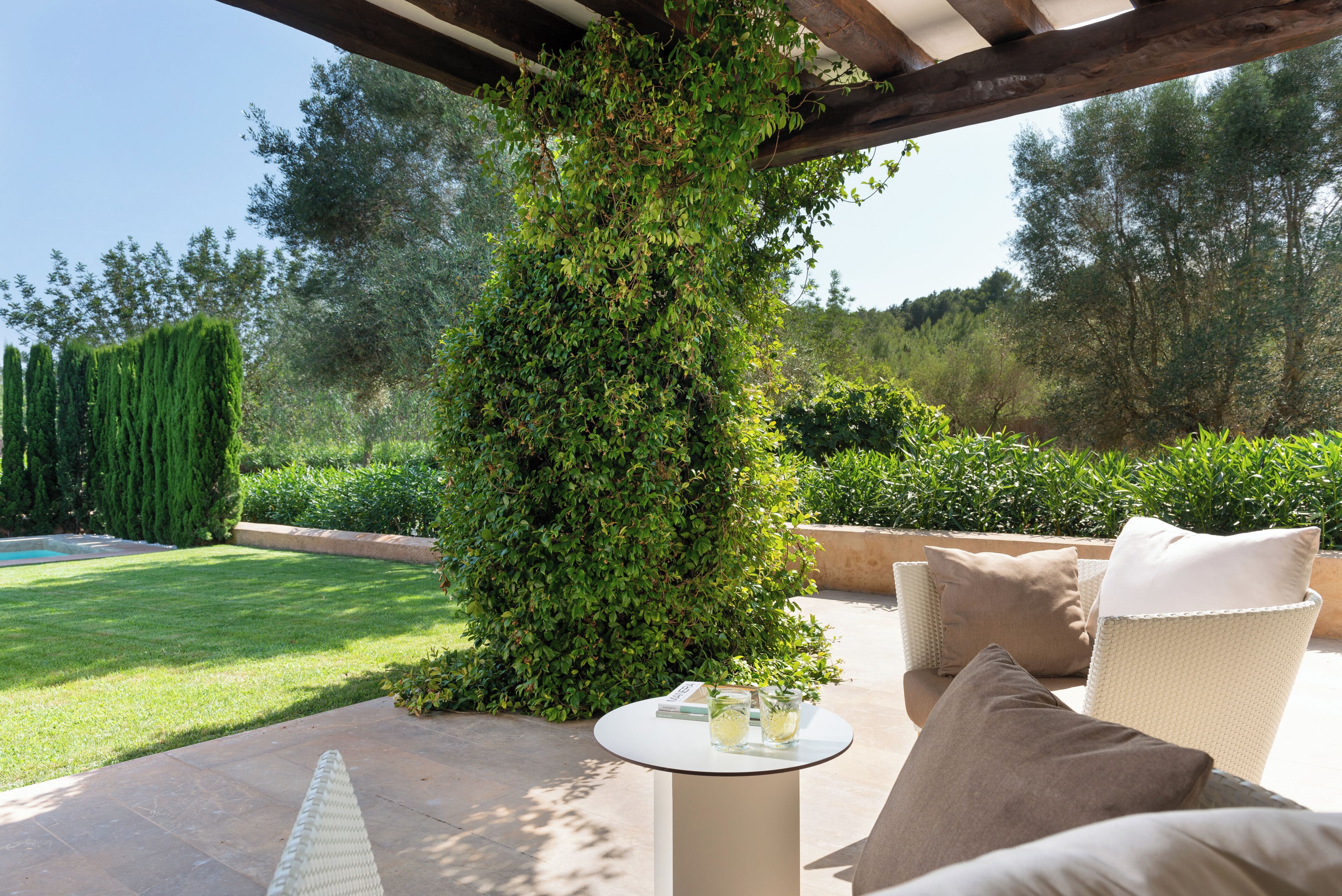 Eine Terrasse mit einer Pergola, Gartenmöbeln und einem Pool.