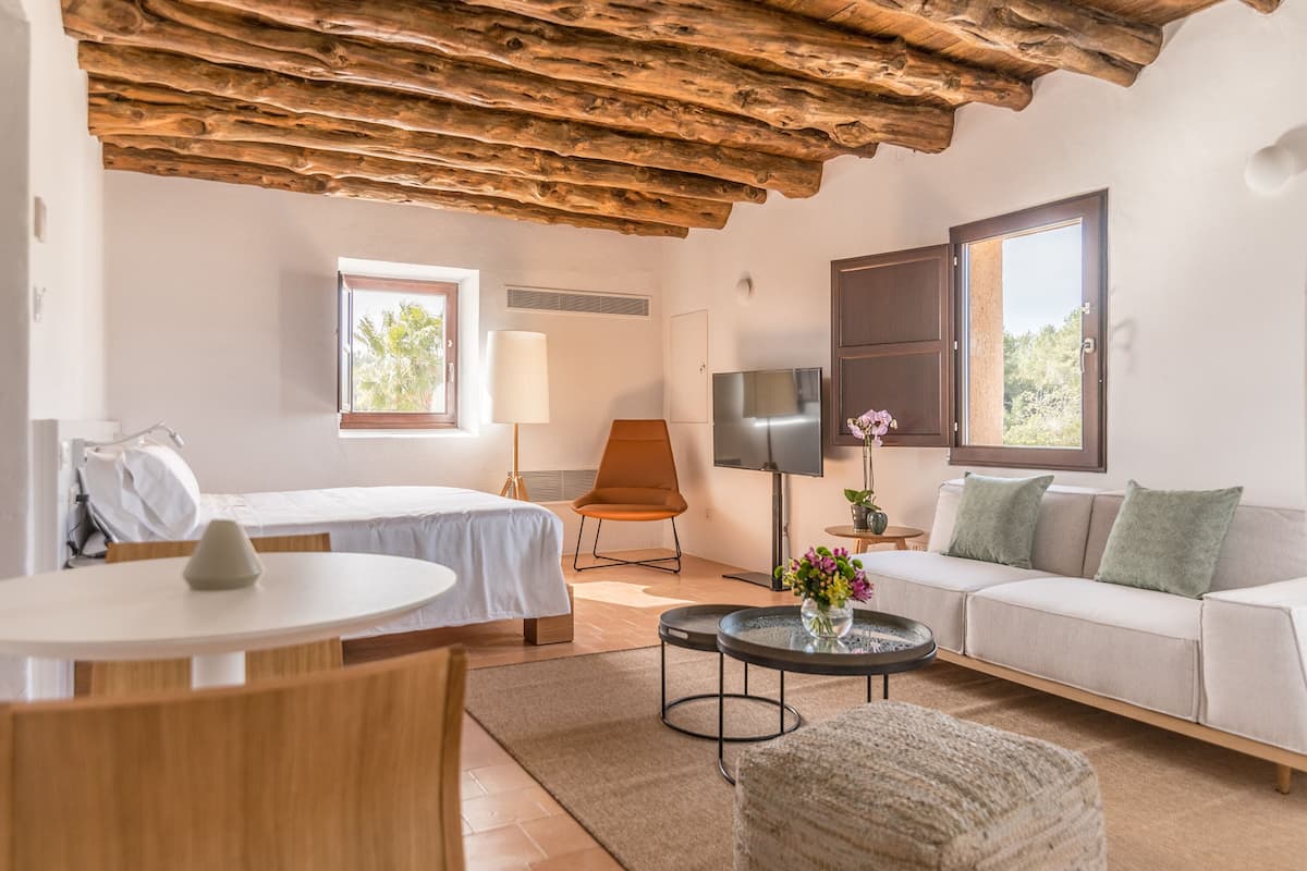 Een moderne kamer met een houten plafond, een bed, een bank, een televisie en een tafel met een bloevas.