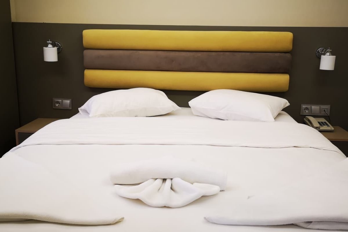 Ein Hotelzimmer mit einem Bett, zwei Nachttischen, einem Telefon und einer Wandleuchte.