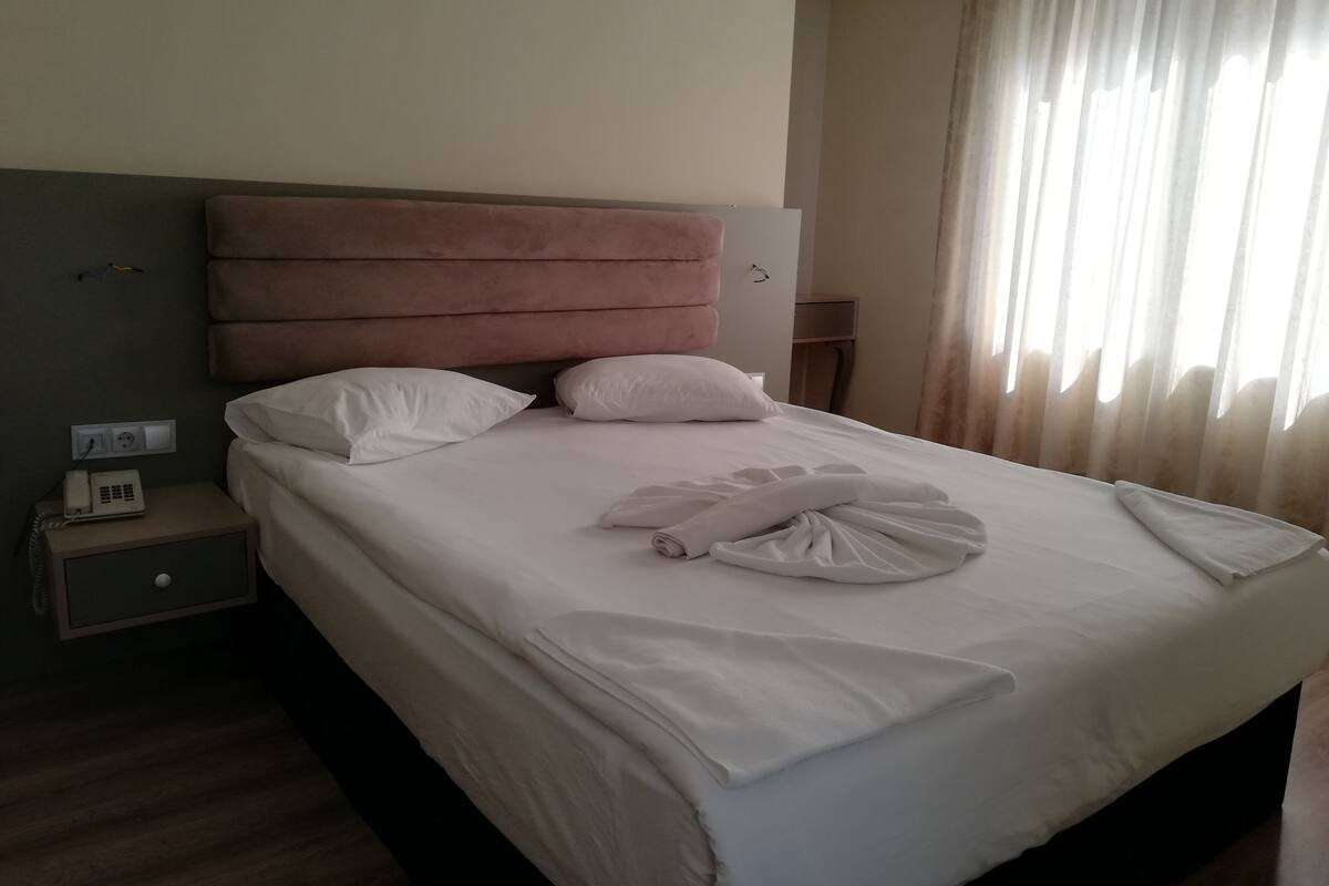 Una habitación de hotel con una cama, una mesita de noche con teléfono y una lámpara.