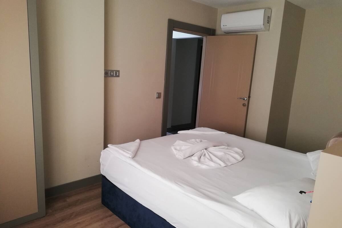 Habitación de hotel con cama, puerta, equipo de aire acondicionado y suelo de madera.