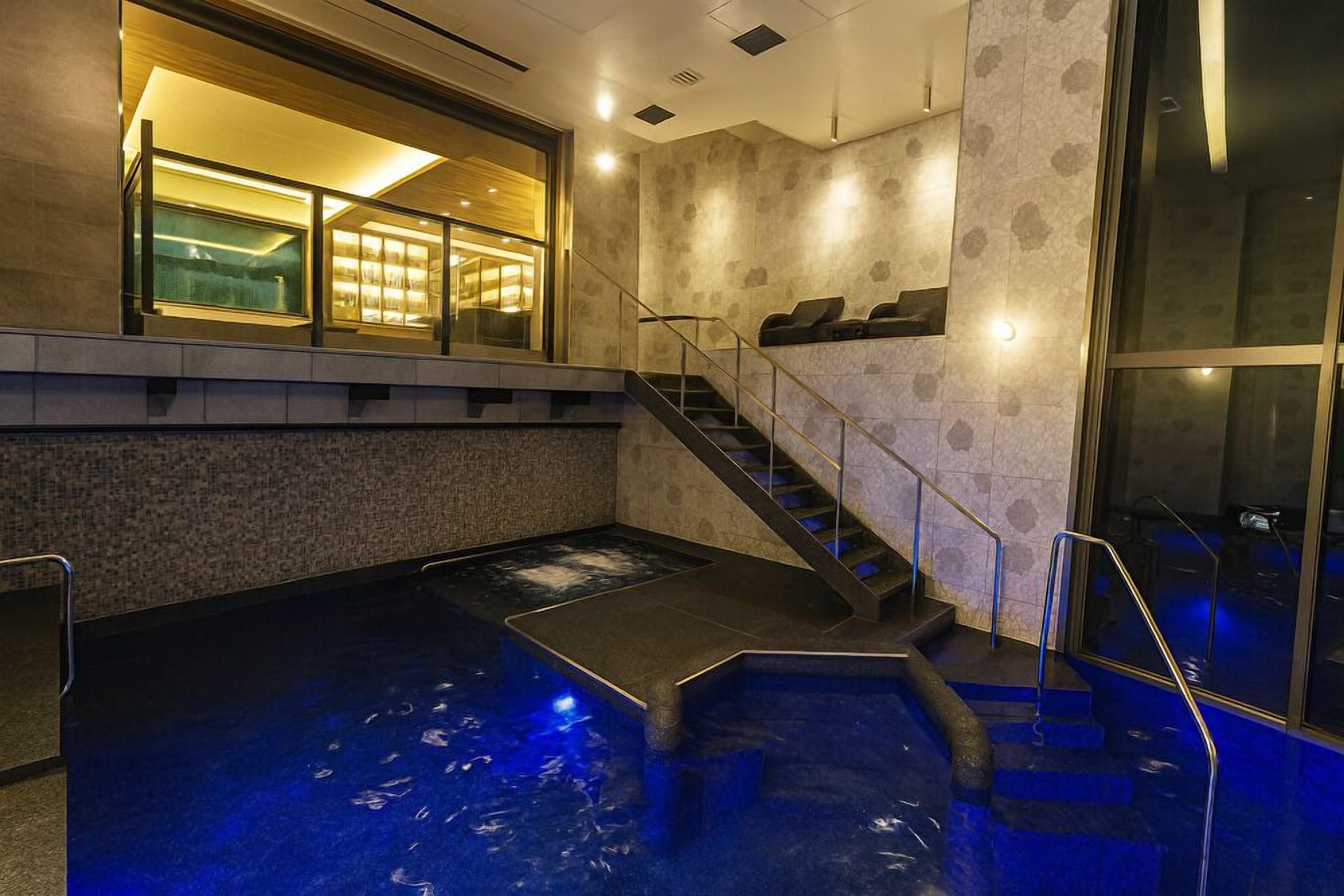 A spa area with a hot tub, stairs, and a glass-enclosed room with lights.
