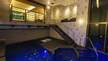 A spa area with a hot tub, stairs, and a glass-enclosed room with lights.