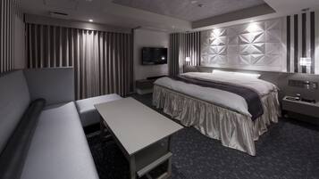 Et moderne hotelværelse med en stor seng, en sofa, et skrivebord og et fjernsyn.